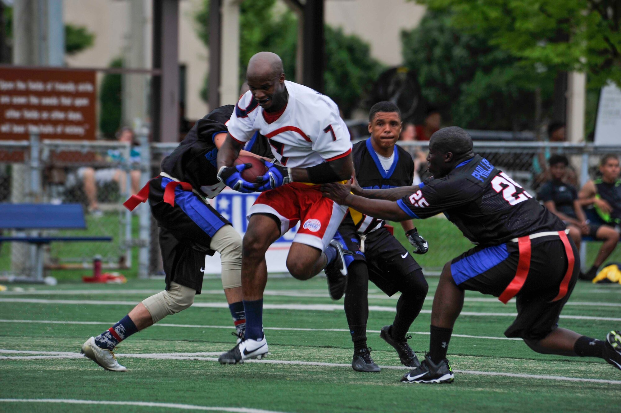 Senior Airman Marcus Pinkney, 51st Aircraft Maintenance Squadron weapons load crew member, tries to run by Camp Carroll Army Base, Republic of Korea, players during the first half of the game at the high school football field on Osan Air Base, ROK, Aug. 2, 2014. Pinkney’s flag was pulled after he achieved a first down for the Mustangs. (U.S. Air Force photo/Senior Airman David Owsianka)