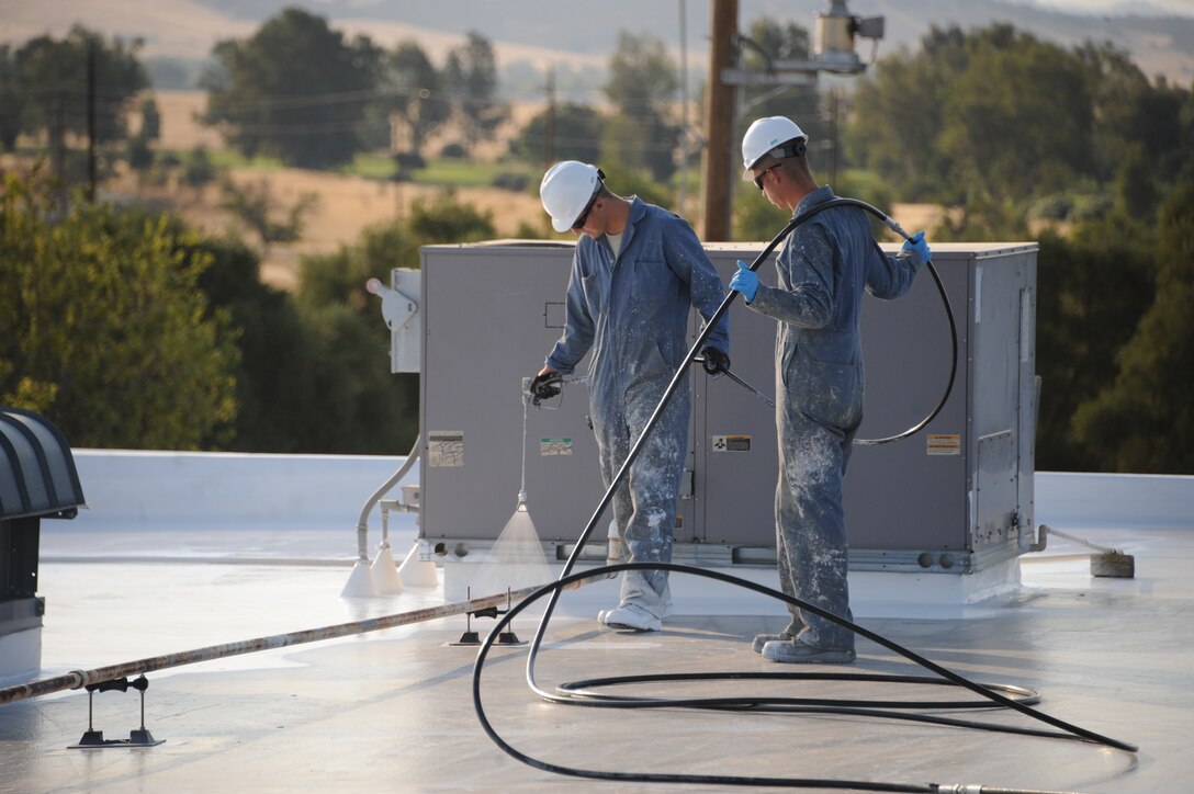 Airmen from the 9th Civil Engineer Squadron roof maintenance team, spray a silicone-based rubberized roofing system on the Base Exchange as part of the roof restoration project July 31, 2014, at Beale Air Force Base, Calif. To date, the roof maintenance team has completed 12 roofs covering more than 90,000 square feet. (U.S. Air Force photo by Airman 1st Class Ramon A. Adelan/ Released)