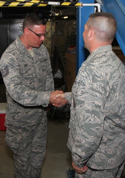 Tech. Sgt. Christopher Parr (left) is presented with a commander's coin by the 932nd security forces commander, Lt. Col. Edward Hunn, for his incredible on-the-go public affairs coverage of an all day training event held in the deep woods and undergrowth.  Sergeant Parr spent time interviewing various security forces Airmen about their jobs and the challenges they go through.  He returned to the office tired, sweaty, several pounds lighter, but with a smile on his face.  "Security forces did some great work out there and I went through the same terrain in some of the same gear to see how it starts to get hot in full gear.  It was a great experience for an Air Force Reserve training weekend," said Sergeant Parr.