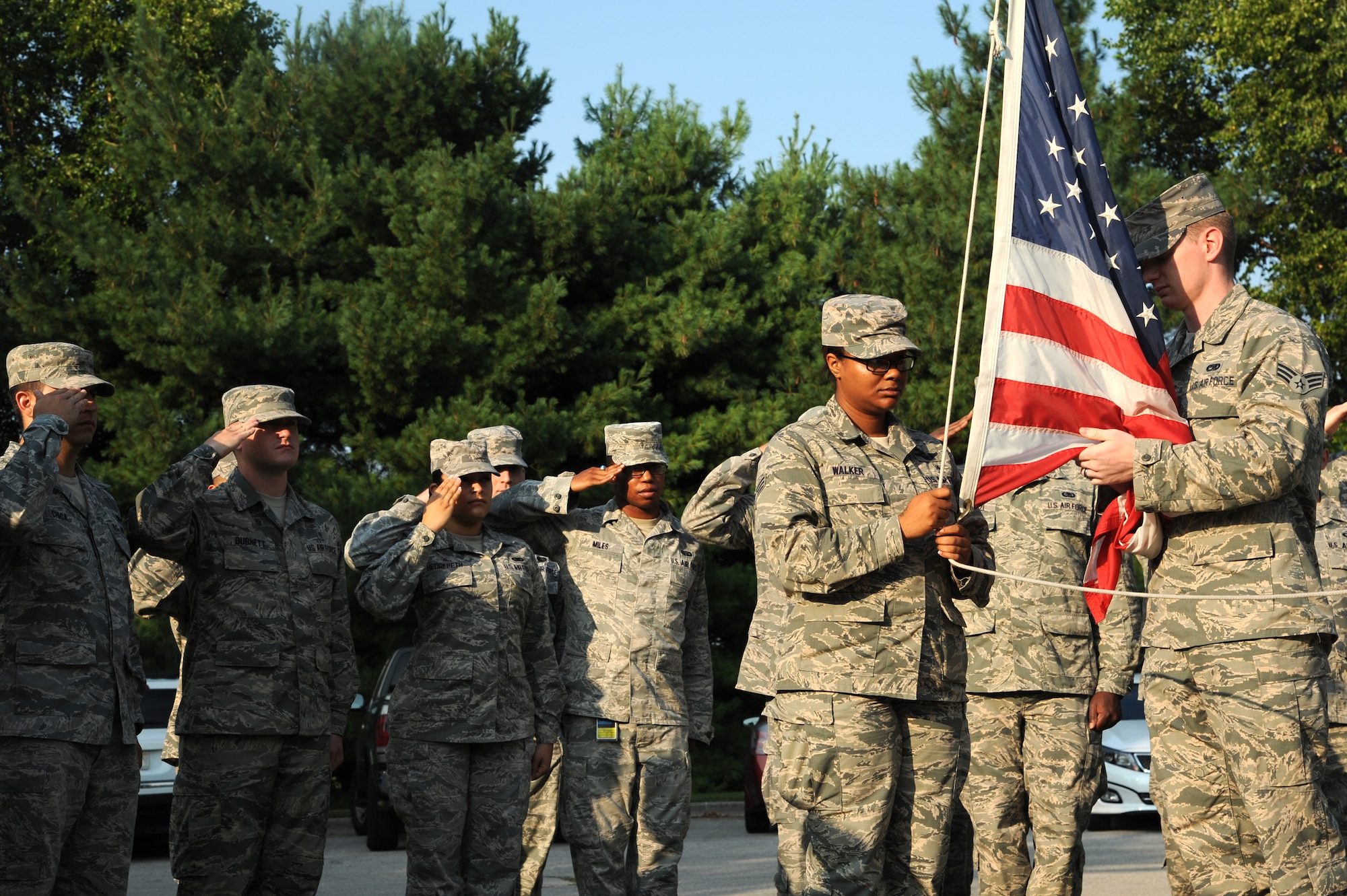 Airman Leadership students salute the flag during a flag detail , July 28, 2014 at Scott Air Force Base, Ill. Every morning ALS students rotate amongst each other to perform a flag detail. Two airman unfold and raise the flag, one student calls the commands while two students are inside giving signals to each other to play the National Anthem. (U.S. Air Force photo/ Senior Airman Tristin English)