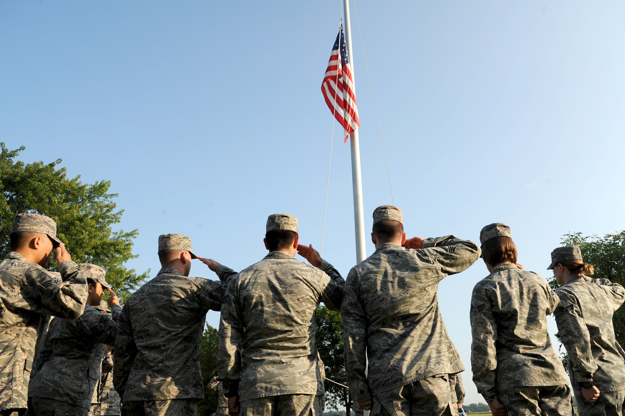 Airman Leadership students salute the flag during a flag detail , July 28, 2014 at Scott Air Force Base, Ill. Every morning ALS students rotate amongst each other to perform a flag detail. Two airman unfold and raise the flag, one student calls the commands while two students are inside giving signals to each other to play the National Anthem. (U.S. Air Force photo/ Senior Airman Tristin English)