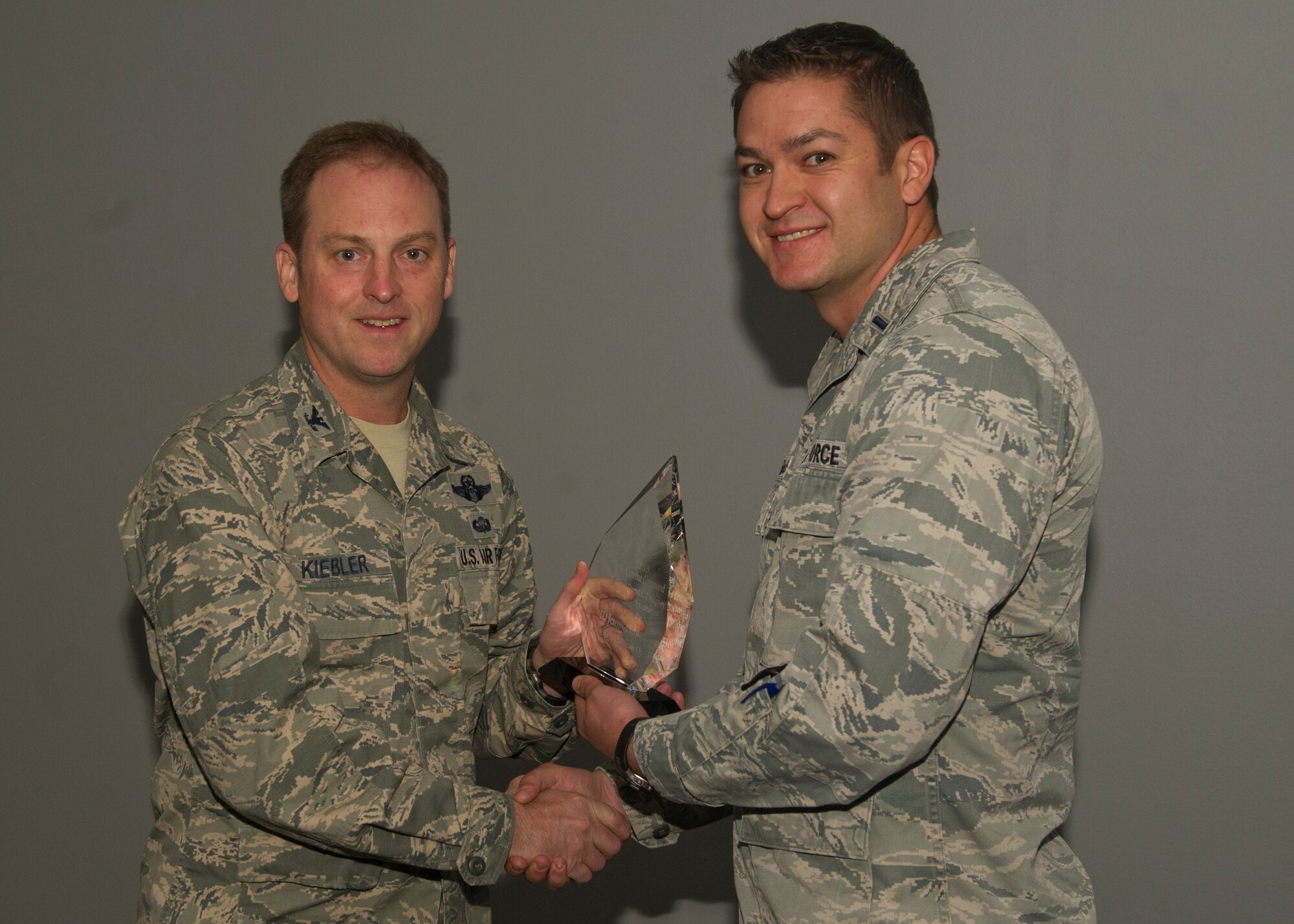 Colonel Robert Kiebler, 49th Wing commander, presents 1st Lt. Jeremy Constantineau, 49th Operations Support Squadron, the Colonel Derrel L. Dempsy Officer of the Year award at Holloman Air Force Base, N.M., Aug. 6. Constantineau was noted for enabling $130 million in research and development testing, directing $54 million in air field construction and leading a flight through an Air Combat Command Compliance Inspection. (U.S. Air Force photo by Airman 1st Class Chase Cannon/ Released)