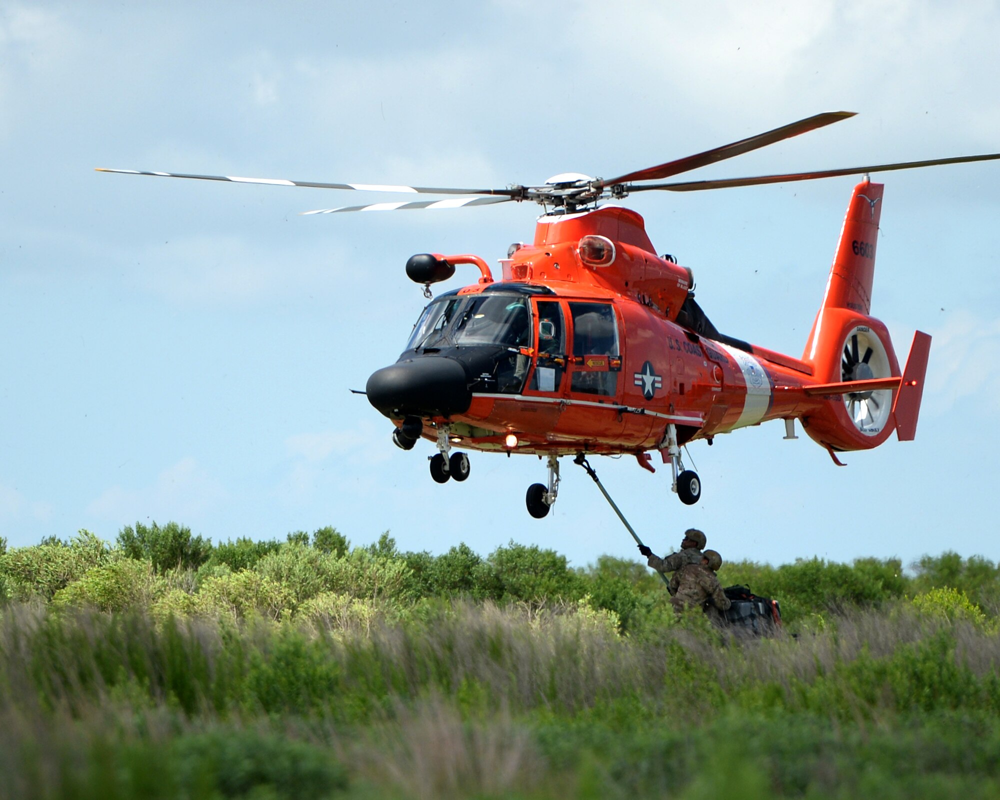 Tactical Air Control Party members with the 147th Air Support Operations Squadron; 147th Reconnaissance Wing, perform sling load operations with a U.S. Coast Guard MH-65 Dauphin during a domestic response resupply exercise June 7, 2014, at Galveston State Park. With the 2014 hurricane season underway, the training allowed the TACPs to exercise response efforts with the Coast Guard members, performing helicopter landing zone operations, aerial resupply and sling load operations.