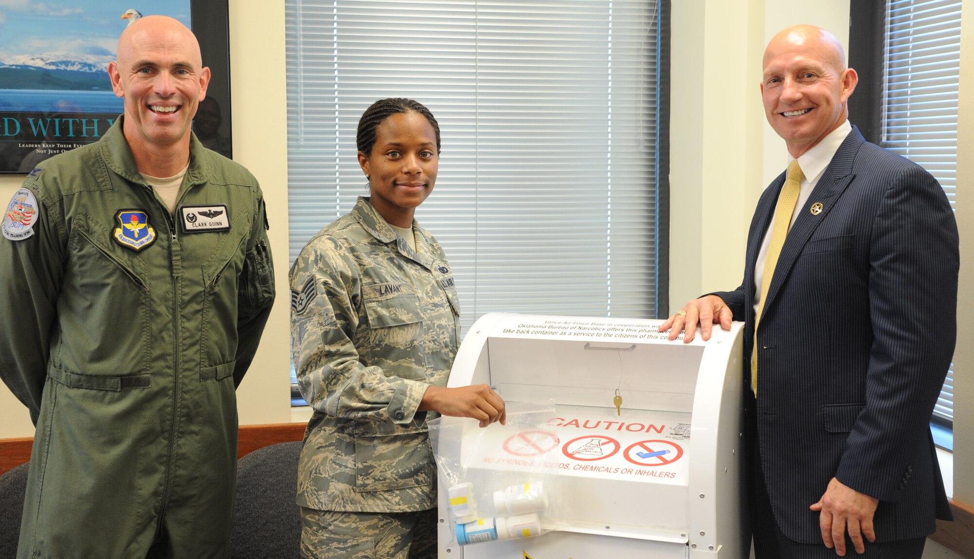 VANCE AIR FORCE BASE, Okla. -- Col. Clark Quinn, left, the 71st Flying Training Wing commander, Staff Sgt. Remmecya Lavant, center, a 71st Security Forces Squadron investigator, and, Darrell Weaver, the Oklahoma Bureau of Narcotics director, make the first drug drop in the Prescription Drug Collection Box’s new location in the Visitor Control Center. (U.S. Air Force photo/Senior Airman Frank Casciotta)