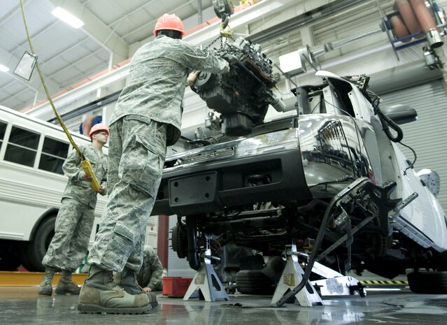 Airman 1st Class Gustavo Acevedo (left) and Staff Sgt. Larry Torres both 99th Logistics Readiness Squadron vehicle mechanics, assist each other in the placement of an engine on a truck at Nellis Air Force Base, Nev. Aug. 5, 2014. The maintenance shop is trained on a wide variety of skill sets to ensure vehicles are mission ready. (U.S. Air Force photo by Airman 1st Class Rachel Loftis)