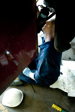 Staff Sgt. Shawn Bailey, 99th Logistics Readiness Squadron vehicle mechanic, assists in the placement of a radiator on fire engine No. 13 at Nellis Air Force Base, Nev. Aug. 5, 2014. The vehicle maintenance shop is a full scale shop that deals with various degrees of vehicles stemming from fire trucks, police cars, trucks and more. (U.S. Air Force photo by Airman 1st Class Rachel Loftis)