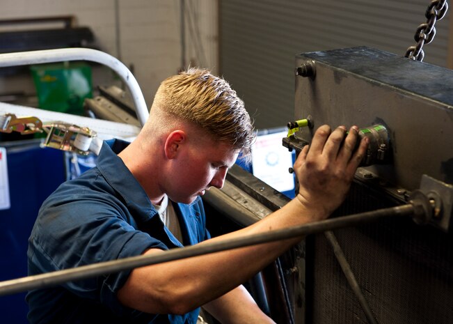 Senior Airman Jake Marjama, 99th Logistics Readiness Squadron fire truck mechanic, helps install a radiator on fire engine No. 13 at Nellis Air Force Base, Nev. Aug. 5, 2014. Fire engines are repaired by vehicle team two technicians who do any and all level of repairs, and specialize in hydraulic system repairs. (U.S. Air Force photo by Airman 1st Class Thomas Spangler)