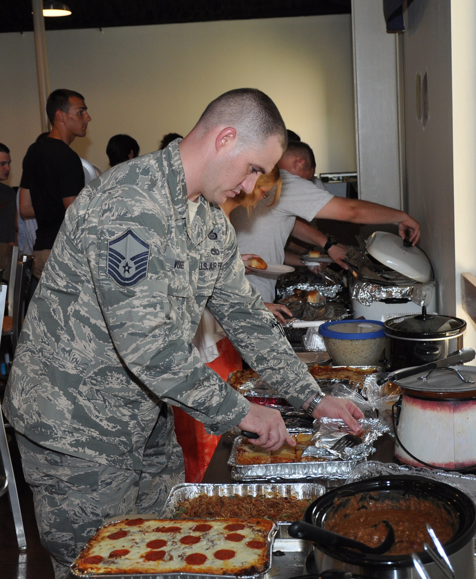 GOODFELLOW AIR FORCE BASE, Texas – Master Sgt. Carl T. Vogel, 316th Training Squadron flight chief, uncovers a casserole dish during the first Top 3 dorm dinner at the Crossroads Student Center here July 29. Top 3 and other volunteers cooked homemade meals to feed hundreds of students. (U.S. Air Force photo/ Senior Airman Joshua Edwards)