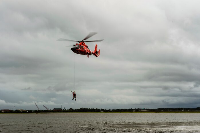 A Coast Guard HH-65 Dolphin pulls a rescue swimmer from the water during a demonstration  Aug. 4, 2014, at U.S.C.G. Sector Charleston, S.C. The demonstration showed the Coast Guard’s rescue capabilities during the Coast Guard’s 224th birthday celebration. (U.S. Air Force photo/Senior Airman George Goslin)
