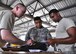 Staff Sgt. Bradley Witkowiak, 647th Logistics Readiness Squadron flight service center craftsman, shows Senior Airman Jayson Prasad and Senior Airman Gilbert Brooks, both 940th LRS materiel managers, how to verify that vital government assets have the correct paperwork with them during an annual routine inspection at Joint Base Pearl Harbor Hickam, Hawaii, July 21. (U.S. Air Force photo by Tech Sgt. Heather Skinkle/Released)