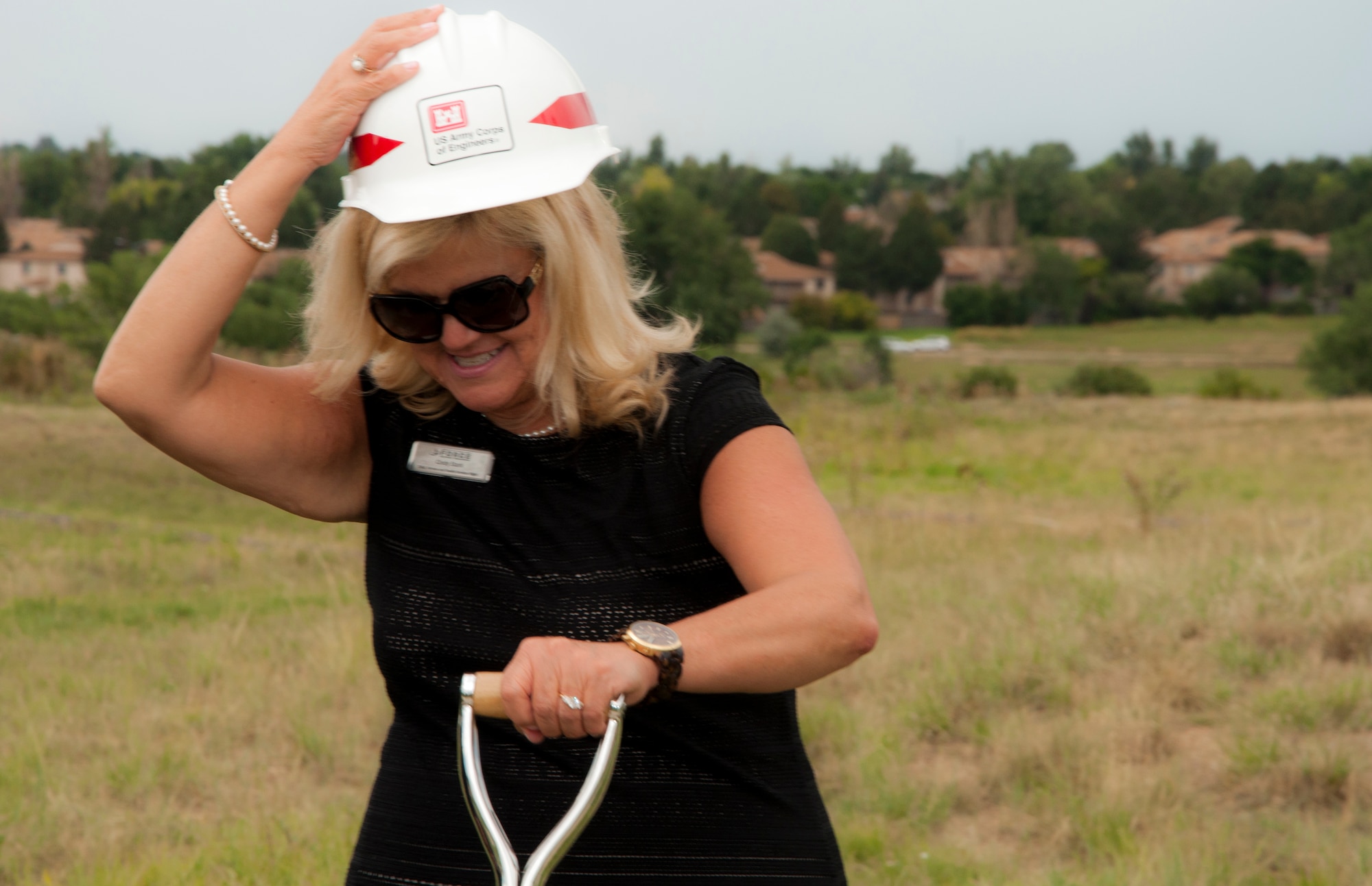 Cindy Stark, 460th Force Support Squadron family member programs chief, adjusts her hardhat for the official groundbreaking for a new accessible community park and an accessible playground Aug. 5, 2014, at the chapel on Buckley Air Force Base, Colo. The community park will be located near the chapel, and the accessible playground will be a renovation of a current playground area. The projects, which are estimated to cost approximately $500,000, are scheduled to be complete in September. (U.S. Air Force photo by Tech. Sgt. Kali L. Gradishar/Released)