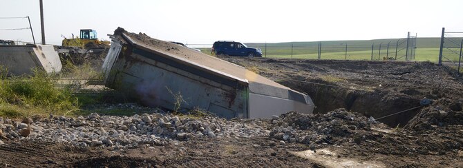 The 110-ton launcher closure door at Launch Facility T-49 is pulled off its rails into a hole Aug. 5, 2014. The site is the last of 50 Minuteman III missile launch silos once operated by the 564th Missile Squadron that are being eliminated from Malmstrom Air Force Base, Mont., in compliance with the New Strategic Arms Reduction Treaty. (Air Force photo/Senior Airman Katrina Heikkinen)