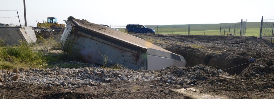 The 110-ton launcher closure door at Launch Facility T-49 is pulled off its rails into a hole Aug. 5, 2014. The site is the last of 50 Minuteman III missile launch silos once operated by the 564th Missile Squadron that are being eliminated from Malmstrom Air Force Base, Mont., in compliance with the New Strategic Arms Reduction Treaty. (Air Force photo/Senior Airman Katrina Heikkinen)