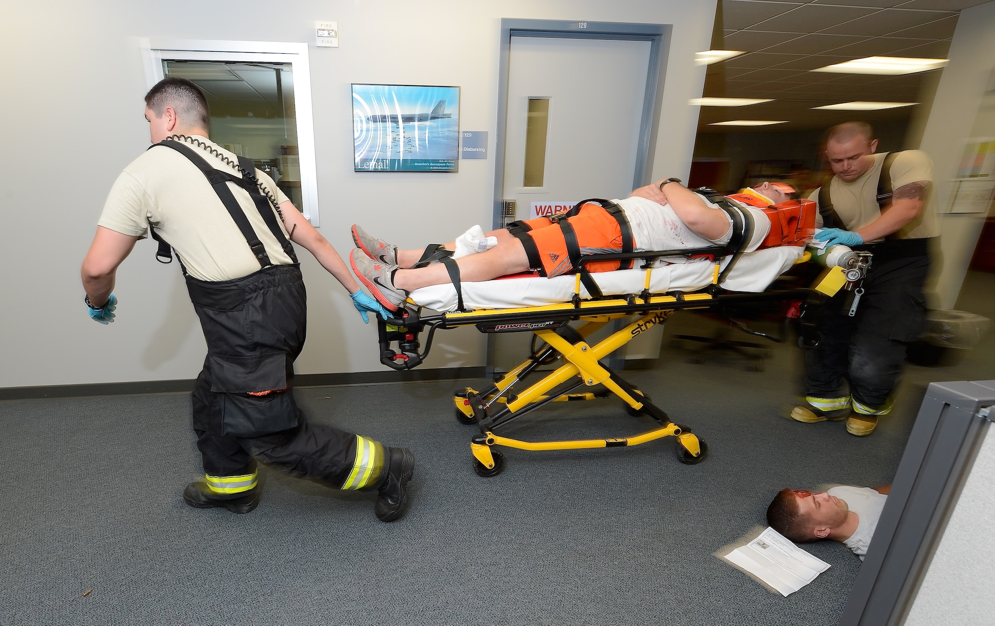 Paramedics from the 436th Civil Engineer Squadron, Fire Department, rush a casualty out of the area on a stretcher while a simulated fatality remains on the floor during an active shooter scenario Aug. 1, 2014, at Dover Air Force Base, Del. (U.S. Air Force photo/Greg L. Davis) 
