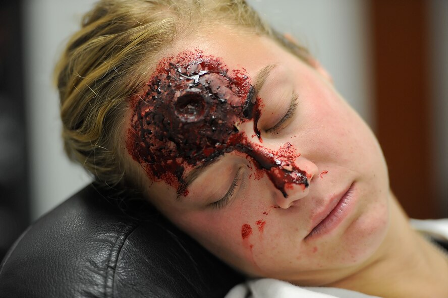 Senior Airman Nicole Silva, 3rd Airlift Squadron C-5M loadmaster, plays the role of a casualty during an active shooter exercise Aug. 1, 2014, at Dover Air Force Base, Del. Extensive make-up was applied to participants for added realism. (U.S. Air Force photo/Greg L. Davis)   