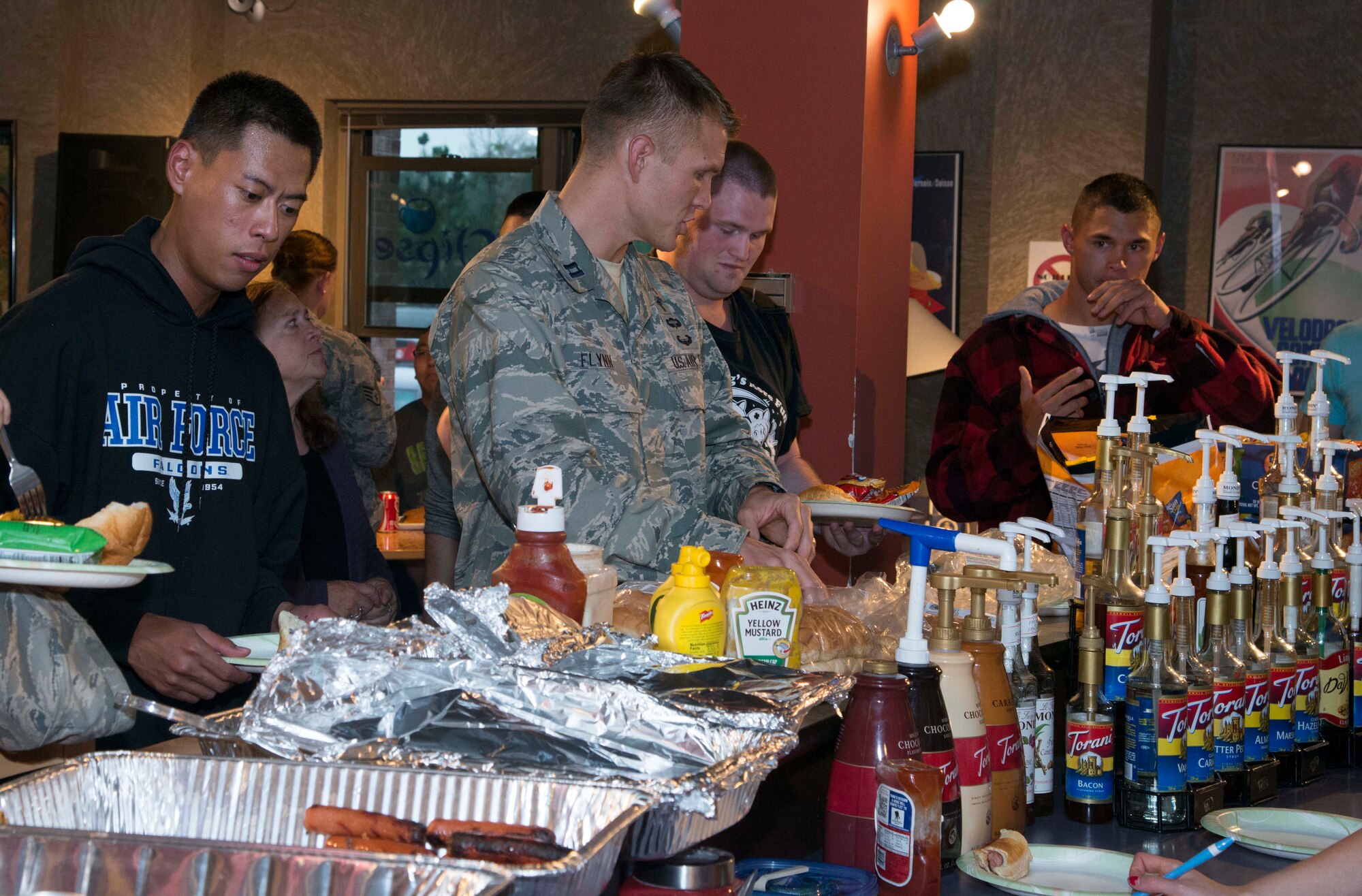 PETERSON AIR FORCE BASE, Colo. — Chaplain (Capt.) Joshua Flynn, 21st Space Wing chaplain, helps Peterson Airmen load up on burgers and hot dogs at the Burger Burn held at the Eclipse Cyber Café July 30. The Burger Burn was organized by the Chapel and was free of charge for anyone in attendance. The Burger Burn was meant to help Airmen meet new people and mingle with friends. (U.S. Air Force photo/Airman 1st Class Rose Gudex)