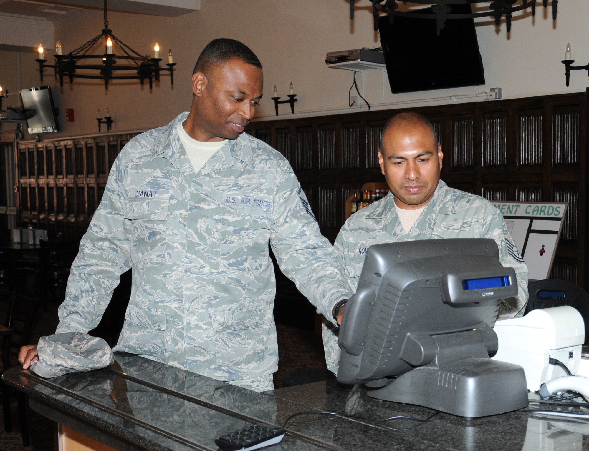 U.S. Air Force Master Sgt. Mohsen Dianat, left, 100th Force Support Squadron Food Service section chief from Oxford, Mich., and U.S. Air Force Tech. Sgt. Javier Romero, 100th FSS Gateway Dining Facility assistant manager from Riverside, Calif., program a cash register July 31, 2014, on RAF Mildenhall, England. The Gateway Dining Facility staff offers a variety of pre-made and cooked-to-order foods available for breakfast, lunch, dinner and a midnight meal. (U.S. Air Force photo/Gina Randall/Released)