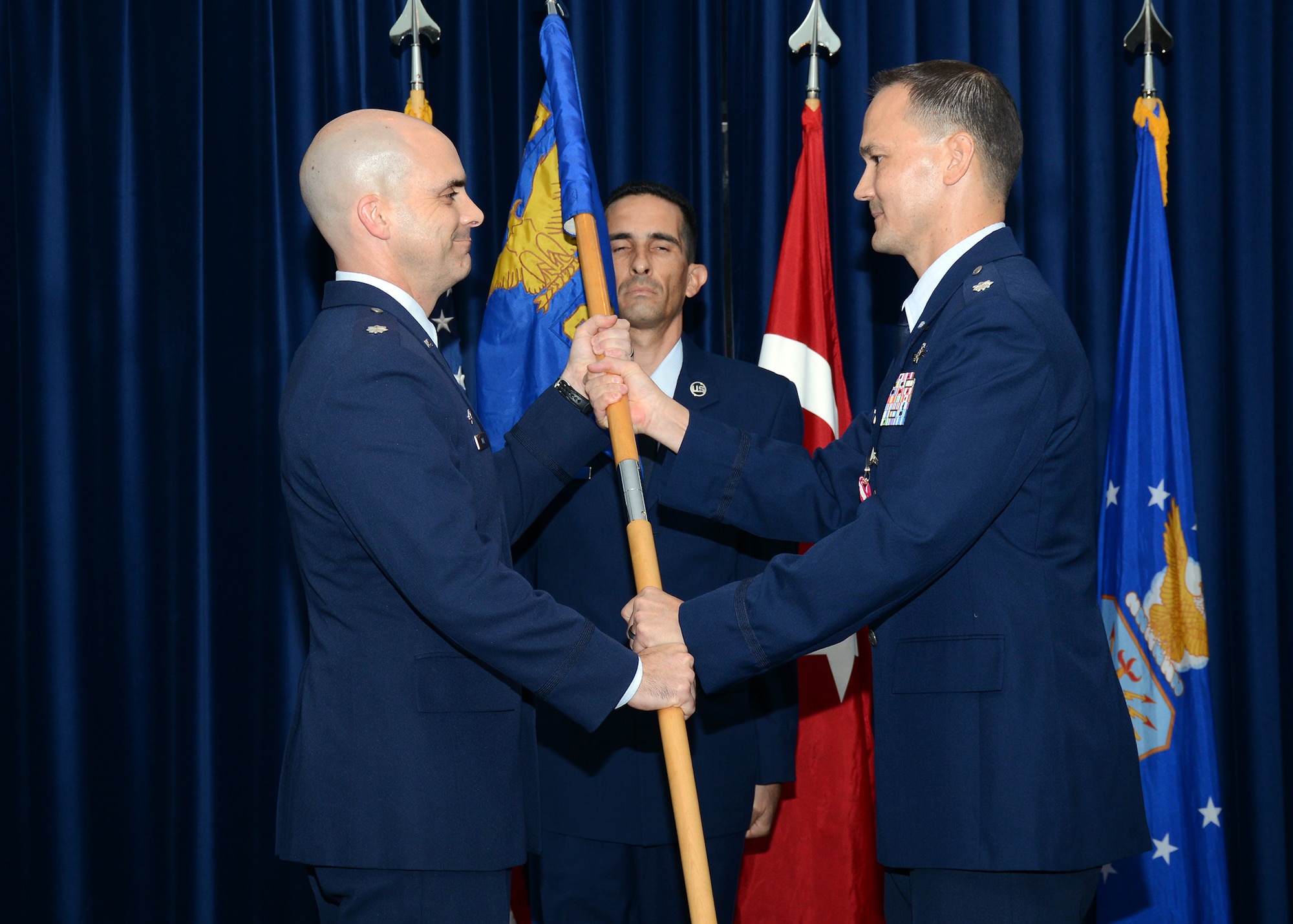 Lt. Col. James Skelton, former commander of the 39th Communications Squadron, passes the guidon to Lt. Col. Russell Voce, 39th Mission Support Group commander, as he relinquishes command during a change of command Aug. 5, Incirlik Air Base Turkey. A change of command ceremony is a tradition that represents a formal transfer of authority and responsibility from the outgoing commander to the incoming commander. (U.S. Air Force photo by Staff Sgt. Veronica Pierce/Released) 
