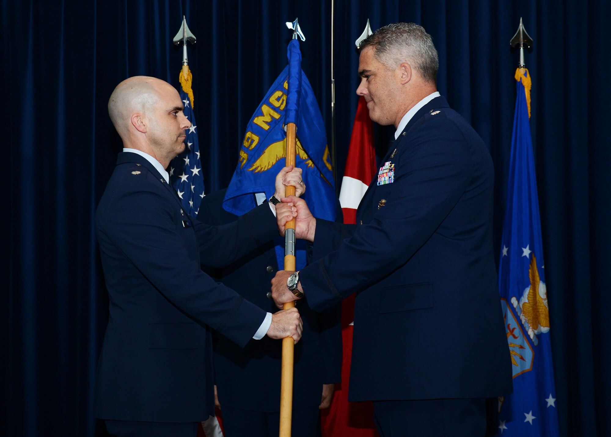 Lt. Col. Russell Voce, 39th Mission Support Group commander, passes the guidon to  Lt. Col. Erin McDonald incoming commander of the 39th Communications Squadron, during a change of command Aug. 5, Incirlik Air Base Turkey. A change of command ceremony is a tradition that represents a formal transfer of authority and responsibility from the outgoing commander to the incoming commander. (U.S. Air Force photo by Staff Sgt. Veronica Pierce/Released) 
