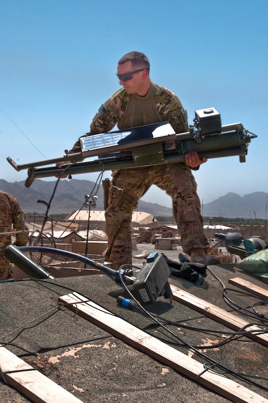 U.S. Air Force Staff Sgt. Scott Tyler takes down a tripod and solar panel of a TMQ-53 tactical weather tower a top a building on Forward Operating Base Pasab, Kandahar Airfield, Afghanistan, Aug. 4, 2014. Tyler, a battlefield weather forecaster, is assigned to the 19th Expeditionary Weather Squadron.