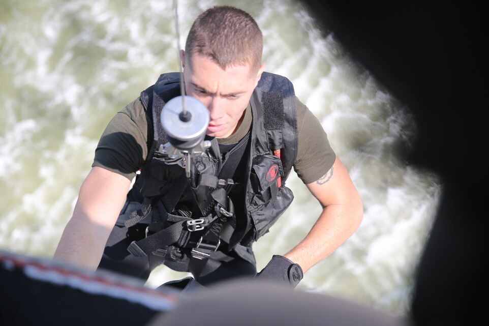 A crew member with Marine Transport Squadron 1 hoists Sgt. Zachary Wood  toward an HH-46E Sea Knight helicopter after assisting central security forces out of Coast Guard Station Hobucken, N.C. during a casualty evacuation drill outside of Marine Corps Air Station Cherry Point, N.C., July 30, 2014. Wood is a rescue swimmer VMR-1.