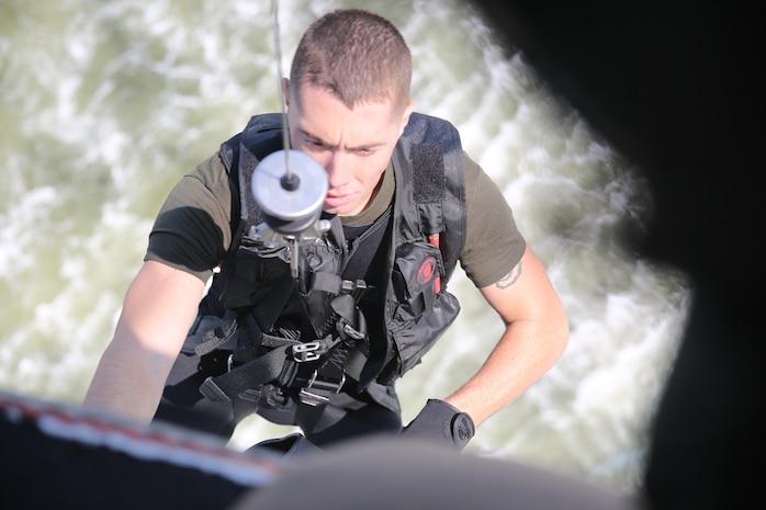 A crew member with Marine Transport Squadron 1 hoists Sgt. Zachary Wood  toward an HH-46E Sea Knight helicopter after assisting central security forces out of Coast Guard Station Hobucken, N.C. during a casualty evacuation drill outside of Marine Corps Air Station Cherry Point, N.C., July 30, 2014. Wood is a rescue swimmer VMR-1.
