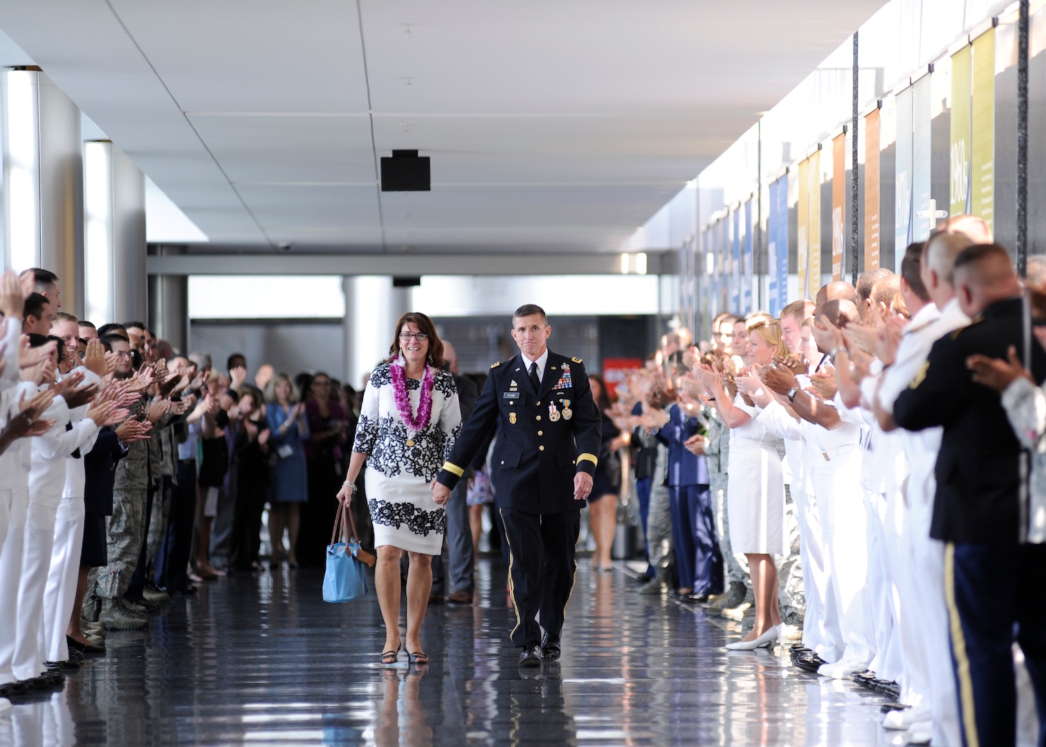 Lt. Gen. Michael Flynn exits DIA Headquarters with his wife, Lori, following his retirement ceremony Aug. 7. Military and civilian members of the workforce lined the hallway to wish the Flynns a fond final farewell.