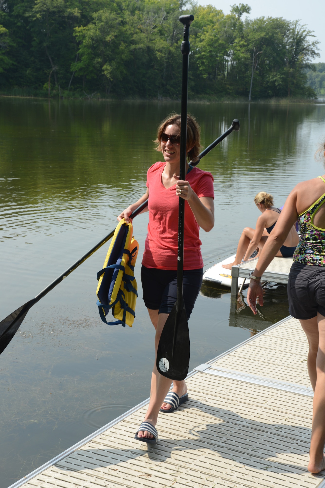 Lt. Col. Micaela Brancato of the 119th Wing carries paddles on the dock at Holbrook Farms Retreat, on Holbrook Lake, Minn., Aug. 1, 2014. Brancato and her husband Lt. Col. Matthew Brancato, also of the 119th Wing, run the retreat and are hosting widows of U.S. military members who lost their lives while serving their country. (U.S. Air Force photo/Senior Master Sgt. David H. Lipp)