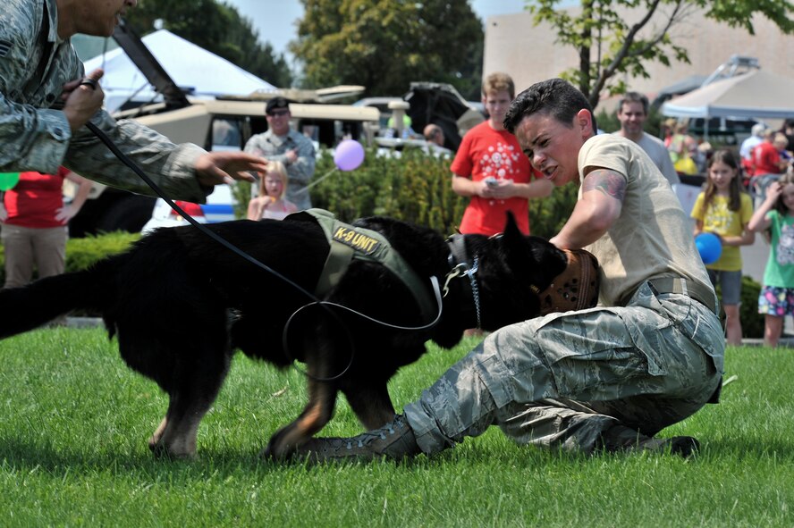 Staff Sgt. Melissa Schmalhorst and a military working dog, Rosso, demonstrate muzzle training which helps the K9 simulate real defense actions during a National Night Out event held in Spokane Valley, Washington, Aug. 5, 2014. Schmalhorst is a Military Working Dog handler with the 92nd Security Forces Squadron at Fairchild Air Force Base, Washington. National Night Out is an annual event throughout the United States designed to heighten awareness of crime and drug prevention, strengthen neighborhood spirit and build partnerships with police. (U.S. Air Force photo by Staff Sgt. Alexandre Montes/Released)