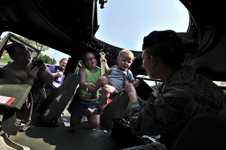 Senior Airman Brianne Berg places a child in the sling of a gunner seat inside a Humvee during a National Night Out event held in Spokane Valley, Washington, Aug. 5, 2014. Berg is a member with the 92nd Security Forces Squadron at Fairchild Air Force Base, Washington. National Night Out is an annual event throughout the United States designed to heighten awareness of crime and drug prevention, strengthen neighborhood spirit and build partnerships with police. (U.S. Air Force photo by Staff Sgt. Alexandre Montes/Released) 
