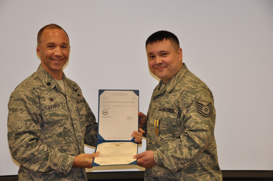Lt. Col. John Graver, 304th Rescue Squadron commander, presents Tech. Sgt. Carl Valentine the Air Force Commendation Medal, Aug. 2, 2014. The 304th RQS is trained and equipped to deploy combat rescue officers, pararescuemen, and support personnel worldwide in support of U.S. national security interests. (U.S. Air Force photo/Staff Sgt. Daniel Delgado)
