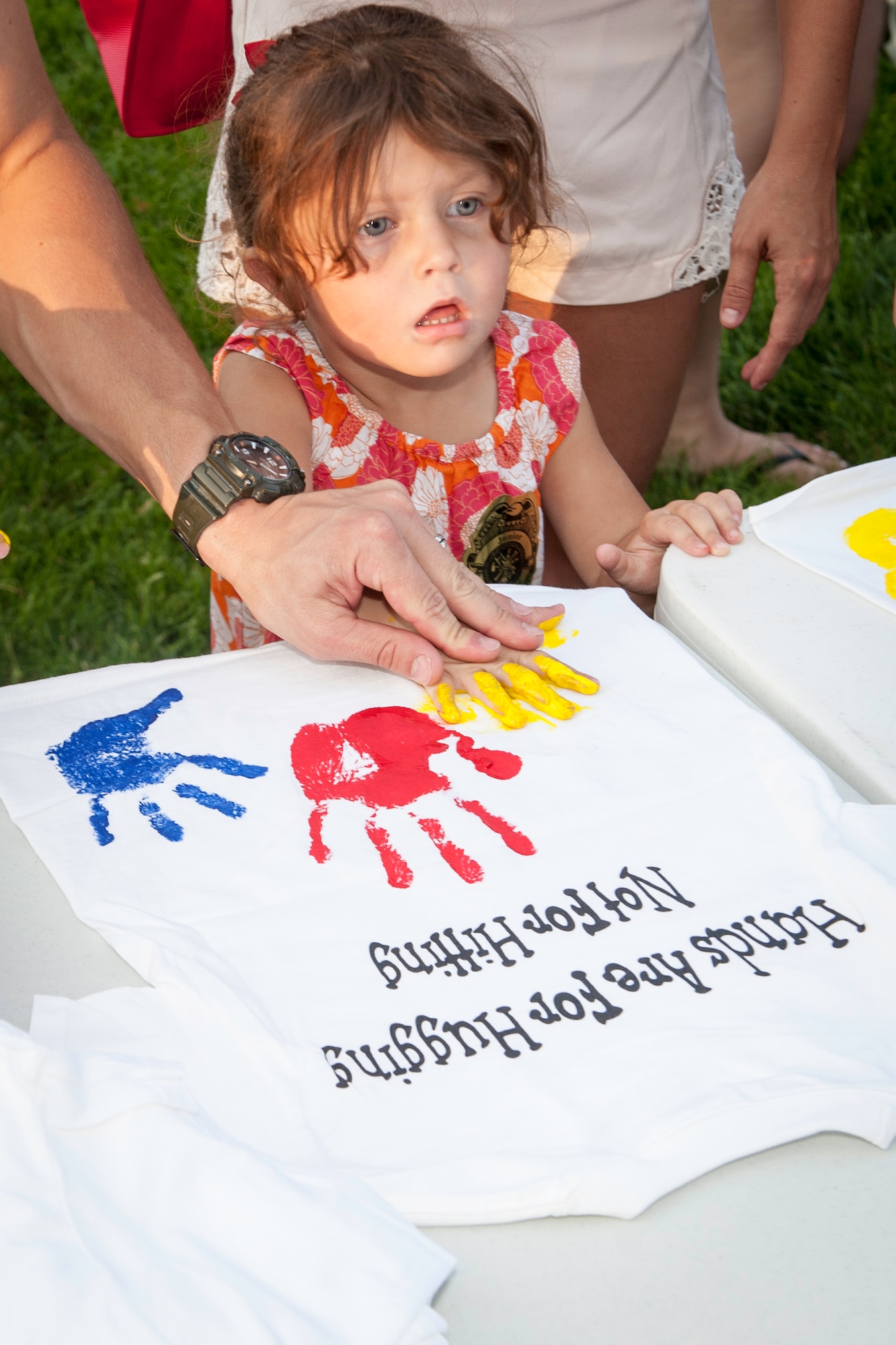 A Fairchild child uses her hand to paint on a Family Advocacy t-shirt during the installation’s National Night Out celebration at Fairchild Air Force Base, Washington, Aug. 5, 2014. The event is held across the country to help prevent crime and drugs from entering “our” neighborhoods. (U.S. Air Force photo by Staff Sgt. Benjamin W. Stratton/Released)