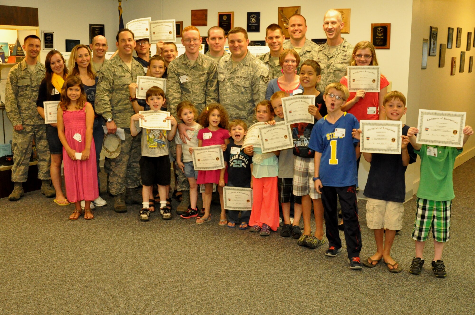 Members of the 55th Strategic Communications Squadron and their children pose for a group photo Aug. 7 at the Defense Satellite Communications System building after receiving certificates of recognition. The squadron commander, Lt. Col. Scott Stevens presented the certificates which stated there were now officially honorary members of the 55th SCS. (U.S. Air Force photo by Staff Sgt. Rachelle Blake)