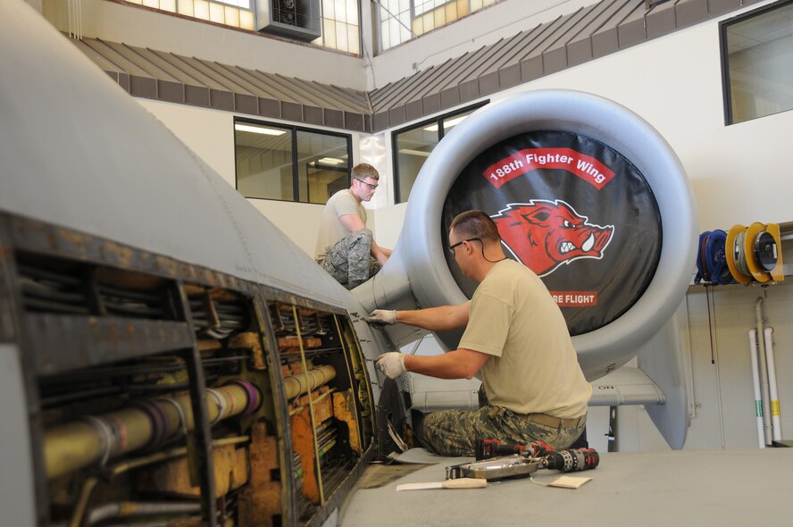 Senior Airman Sean Liggett, left, and Tech. Sgt. Aaron Thorne, both members of the former 188th Aircraft Maintenance Squadron, remove panels from and A-10C Thunderbolt II "Warthog" (aircraft Tail No. 586) to accomplish phase work cards. The purpose of the phase inspection is to ensure the aircraft's reliability and to prevent future issues. This aircraft was the last phase accomplished at Ebbing Air National Guard Base, Fort Smith, Arkansas. Recently, the wing held a conversion ceremony changing from a manned flying mission to a remotely piloted aircraft/intelligence, surveillance and reconnaissance mission. (U.S. Air National Guard photo by Senior Airman John Hillier/released)