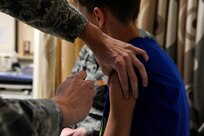 Senior Airman Kelly Boos, left, administers multiple vaccinations to Andrew Mitchell Aug. 6, 2014, at the Joint Base San Antonio-Randolph Immunizations Clinic. Boos is an aerospace medical technician and Mitchell is the son of Master Sgt. Kimberly Mitchell. Mitchell is the  NCO in charge at the ear, nose and throat clinic. (U.S. Air Force photo/Desiree N. Palacios)