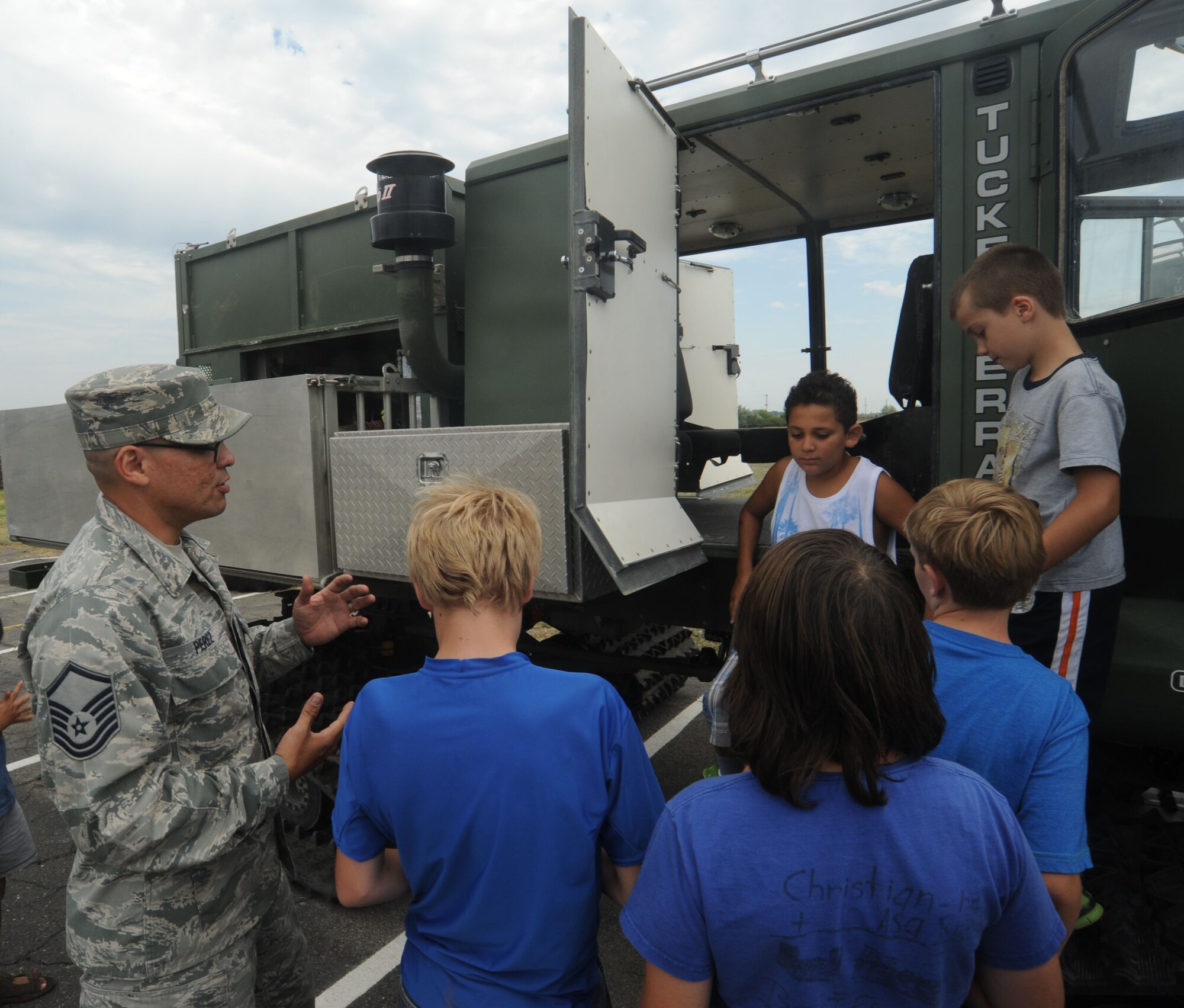 Master. Sgt. Jose Perez explains the Tucker all-terrain vehicle to children from the Northeast Youth Center of Spokane summer camp at Fairchild Air Force Base, Washington, Aug. 1, 2014. Perez is the 336th Training Support Squadron vehicle management superintendent. The children were on a tour of Fairchild’s Survival School area for their military theme week. (U.S. Air Force photo by Airman 1st Class Sam Fogleman/Released)
