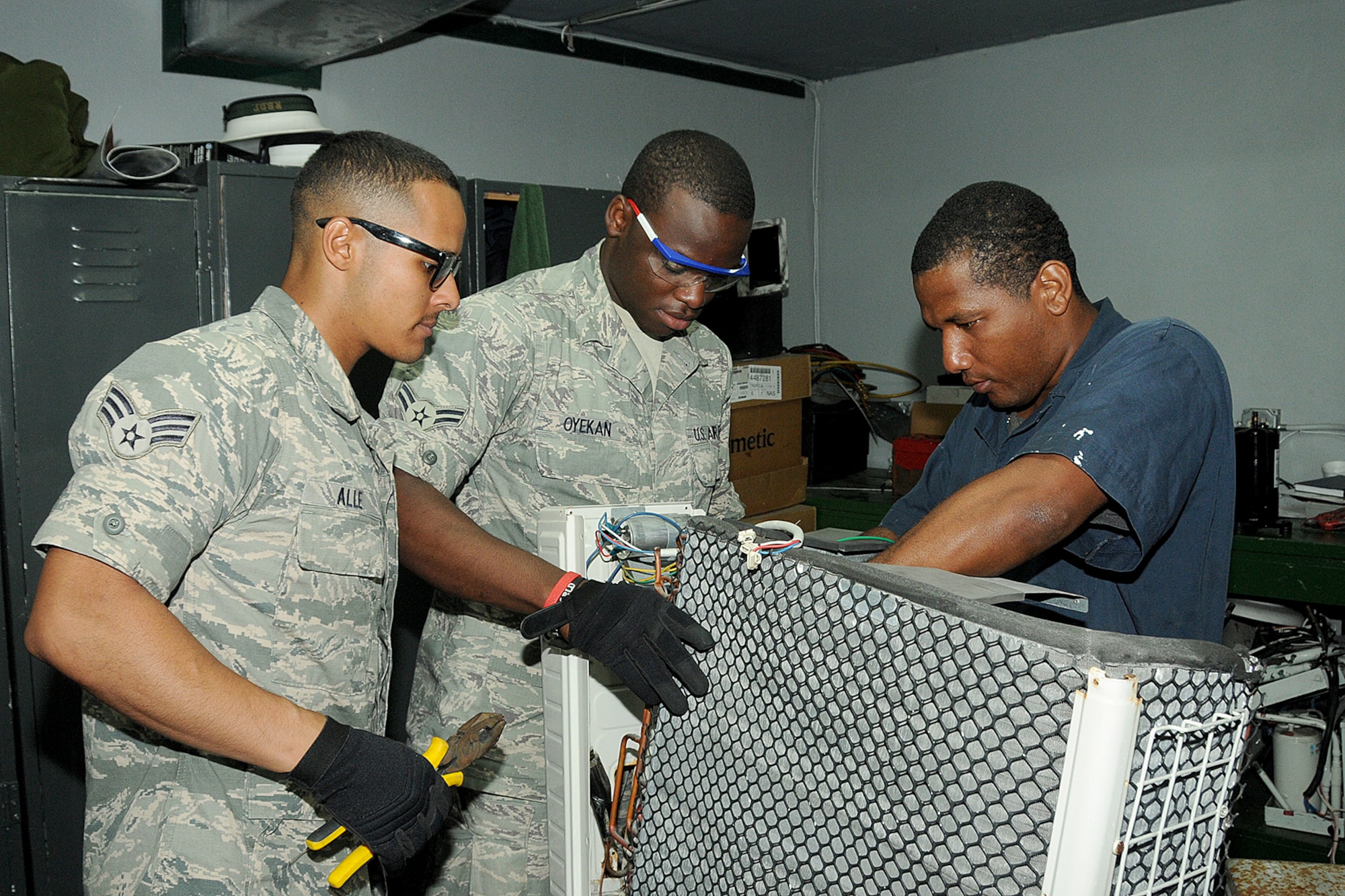 Senior Airman Christian Dario Alee (left), Airman First Class Oluwatomisin Nmn Oyekan of the Rhode Island Air National Guard,143d Airlift Wing, Civil Engineering Squadron, replaces the compressor of an air conditioning unit with their  Bahamian counterpart Marine Mechanic Neil Nairn of the Royal Bahamas Defence Force (RBDF), HVAC shop at the Coral Harbour Base in Nassau, Bahamas on June 16, 2014 for their inaugural group DFT (Deployment For Training) to support the RBDF in conjunction with the National Guard State Partnership Program (SPP). National Guard Photo by Master Sgt John McDonald (RELEASED)