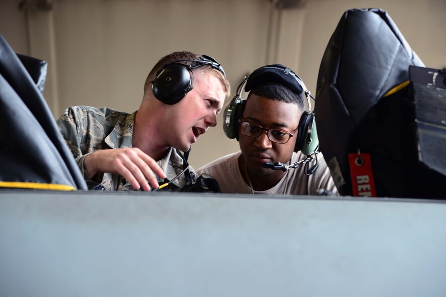 Senior Airmen Justin Brummel and Carl Dunbar, 35th Aircraft Maintenance Squadron avionics technicians, discuss maintenance options after troubleshooting an F-16 Fighting Falcon at Misawa Air Base, Japan, July 11, 2014. Avionics technicians are responsible for maintaining nearly 50 major systems on the aircraft. (U.S. Air Force photo/Senior Airman Derek VanHorn)