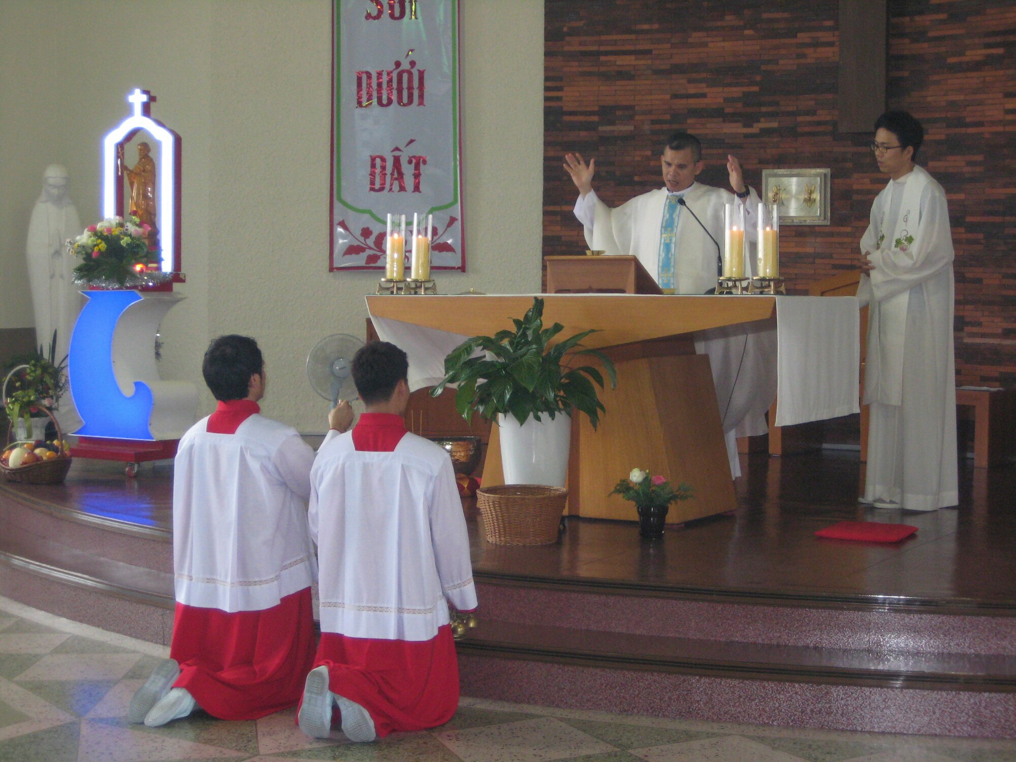 Chaplain (Capt.) Thienan Tran, 51st Fighter Wing chaplain, leads his church in prayer during a Catholic Mass while altar servers kneel to prepare incense at Cho-Rang Catholic Church in Busan, Republic of Korea Aug. 3, 2014. Tran spends his off-duty time providing Catholic Mass to communities of Vietnamese labor workers.