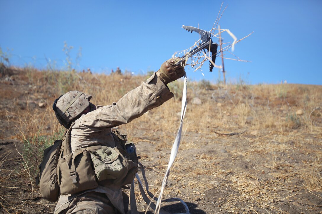 Marine Corps Lance Cpl. Douglas Jorgensen tosses a grappling hook to search  the area for notional