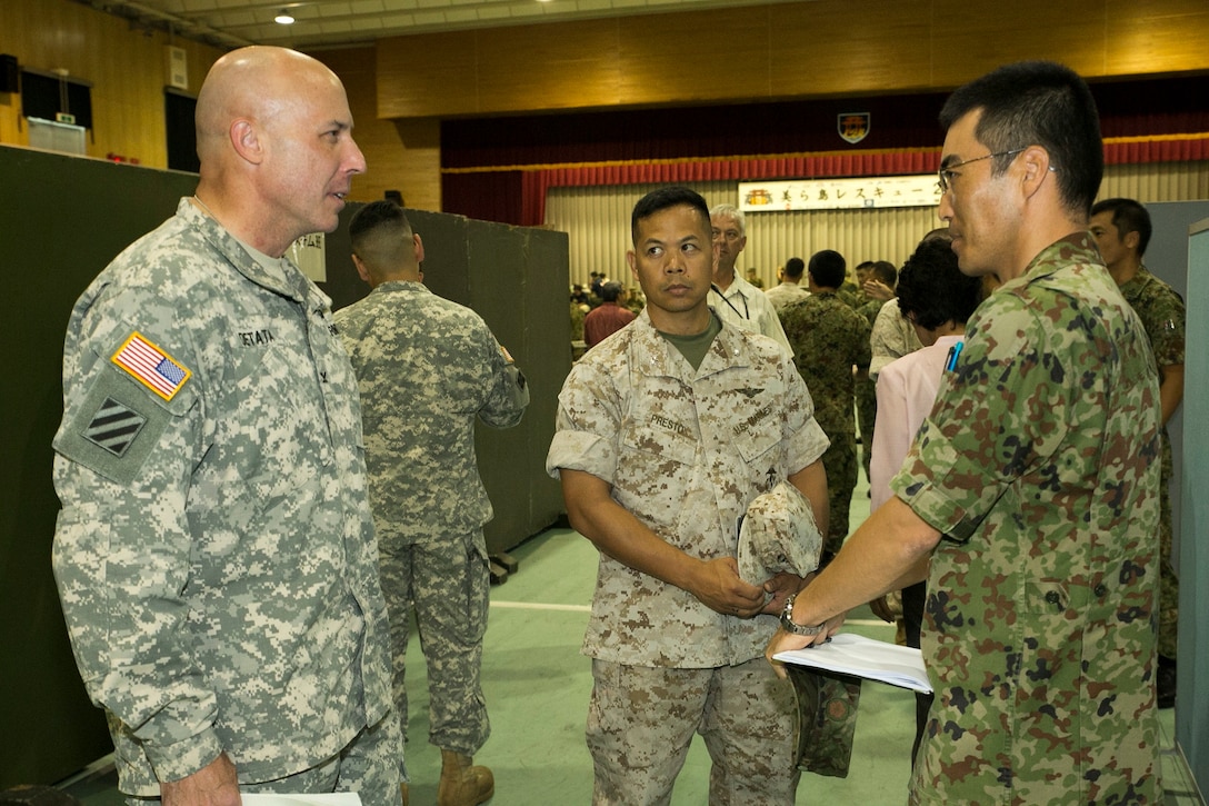 Japan Ground Self-Defense Force Capt. Takehiro Oishi, right, discusses responses to a simulated earthquake with U.S. Army Col. David W. Detata, left, and U.S. Marine Corps Lt. Col. Donald J. Presto during a mock disaster response training July 23 at the Camp Naha gymnasium on Camp Naha, Okinawa. The event united members of the JGSDF 15th Brigade and U.S. service members and federal employees stationed on Okinawa. The training used assessments of past disasters, operations and exercises to stage and rehearse the day’s scenario, according to Oishi. Oishi is a liaison with the Liaison Office, 15th Brigade, JGSDF. Detata is a Los Gatos, California, native and chief of the Okinawa Area Field Office, U.S. Forces Japan. Presto is a Virginia Beach, Virginia, native and the Japan exercise and engagement officer with G-3, operations, III Marine Expeditionary Force. (U.S. Marine Corps photo by Lance Cpl. Pete Sanders/Released)