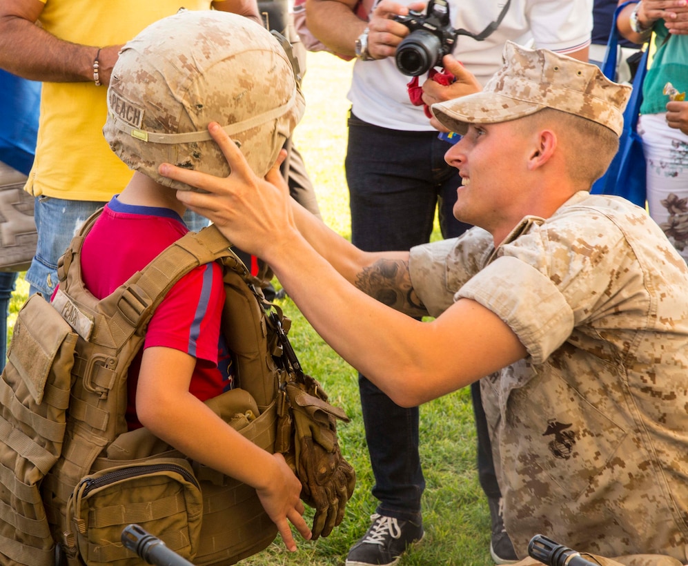 Cpl. Kevin Peach helps fit a Kevlar helmet on a child at the National Night Out event aboard Naval Air Station Sigonella, Italy, Aug. 5, 2014. Marines and Sailors with the second iteration of SP-MAGTF Africa 14 participated in the event with a static display of weapons, an Explosive Ordnance Disposal robot, and two vehicles organic to the Marine Corps. SP-MAGTF Africa continues to build relationships with the community while simultaneously strengthening U.S. Africa Command and U.S. Marine Corps Forces Africa’s ability to assist partner nations in addressing security challenges in the region. (U.S. Marine Corps photo by Cpl. Shawn Valosin)