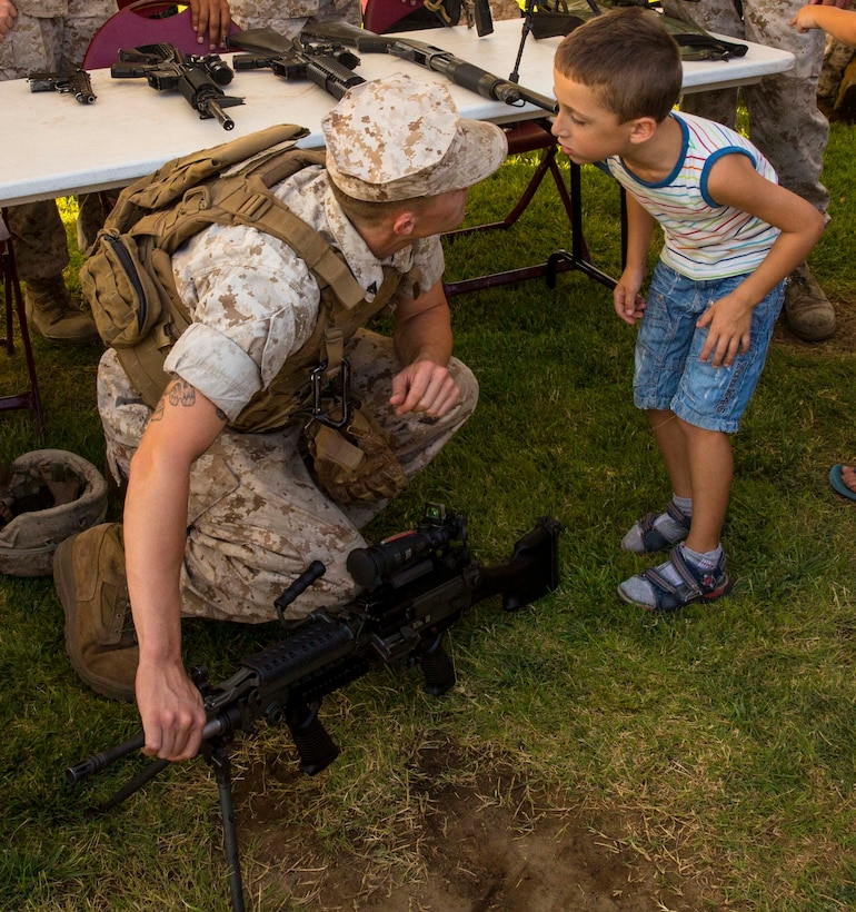 Cpl. Kevin Peach explains parts of various weapons systems to a child at the National Night Out event aboard Naval Air Station Sigonella, Italy, Aug. 5, 2014. Marines and Sailors with the second iteration of SP-MAGTF Africa 14 participated in the event with a static display of weapons, an Explosive Ordnance Disposal robot, and two vehicles organic to the Marine Corps. SP-MAGTF Africa continues to build relationships with the community while simultaneously strengthening U.S. Africa Command and U.S. Marine Corps Forces Africa’s ability to assist partner nations in addressing security challenges in the region. (U.S. Marine Corps photo by Cpl. Shawn Valosin)