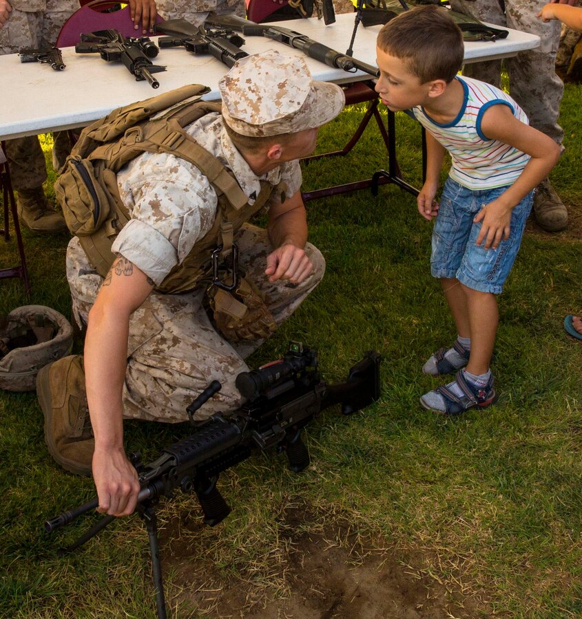 Cpl. Kevin Peach explains parts of various weapons systems to a child at the National Night Out event aboard Naval Air Station Sigonella, Italy, Aug. 5, 2014. Marines and Sailors with the second iteration of SP-MAGTF Africa 14 participated in the event with a static display of weapons, an Explosive Ordnance Disposal robot, and two vehicles organic to the Marine Corps. SP-MAGTF Africa continues to build relationships with the community while simultaneously strengthening U.S. Africa Command and U.S. Marine Corps Forces Africa’s ability to assist partner nations in addressing security challenges in the region. (U.S. Marine Corps photo by Cpl. Shawn Valosin)