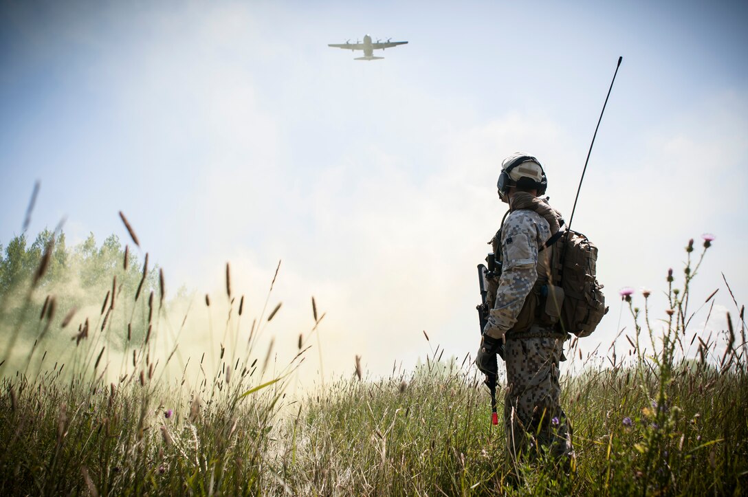 Capt. Armands Rutkis, a Joint Tactical Air Controller from the Latvian armed forces, marks a drop zone with smoke to allow a C-130 Hercules to drop simulated cargo during Operation Northern Strike 2014 near Rogers City, Mich. on Aug. 5, 2014. The C-130 is based with the 182nd Airlift Wing in Peoria, Ill. Operation Northern Strike 2014 is a joint multi-national combined arms training exercise conducted in Michigan. (U.S. Air National Guard photo/Master Sgt. Scott Thompson)