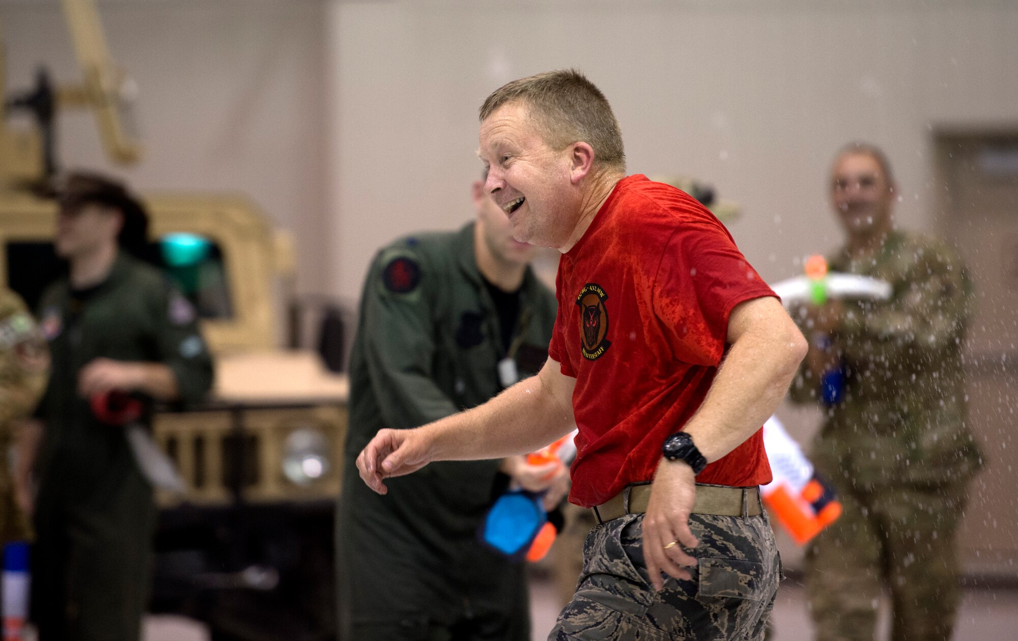 Col. James Cluff, 432nd Wing/432nd Air Expeditionary Wing commander runs through a hangar while being shot with water guns during the inaugural combat dining-in at Creech Air Force Base, Nev., July 11, 2014. The combat dining-in is an 84-year-old Air Force tradition which aims to enhance espirit de corps and build camaraderie with fellow Airmen. (U.S. Air Force photo by 432nd Wing/432nd Air Expeditionary Wing Public Affairs/Released)