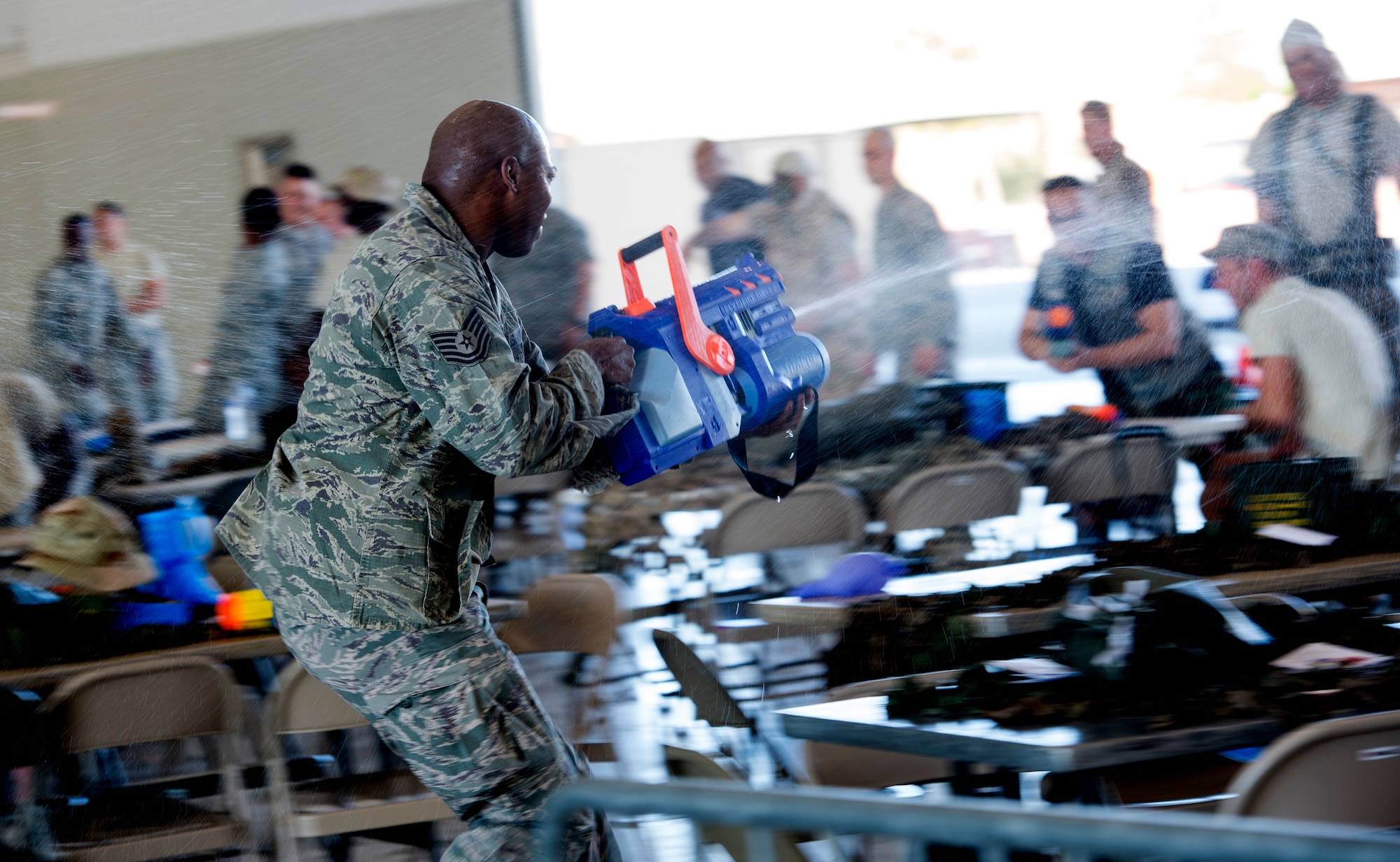 An Airman “attacks” Airmen from other squadrons with a water gun during the inaugural combat dining-in on Creech Air Force Base, Nev., July 11, 2014. Participants brought water balloons and water guns and engaged in friendly water “warfare” to help build camaraderie. (U.S. Air Force photo by Staff Sgt. Adawn Kelsey/Released)
