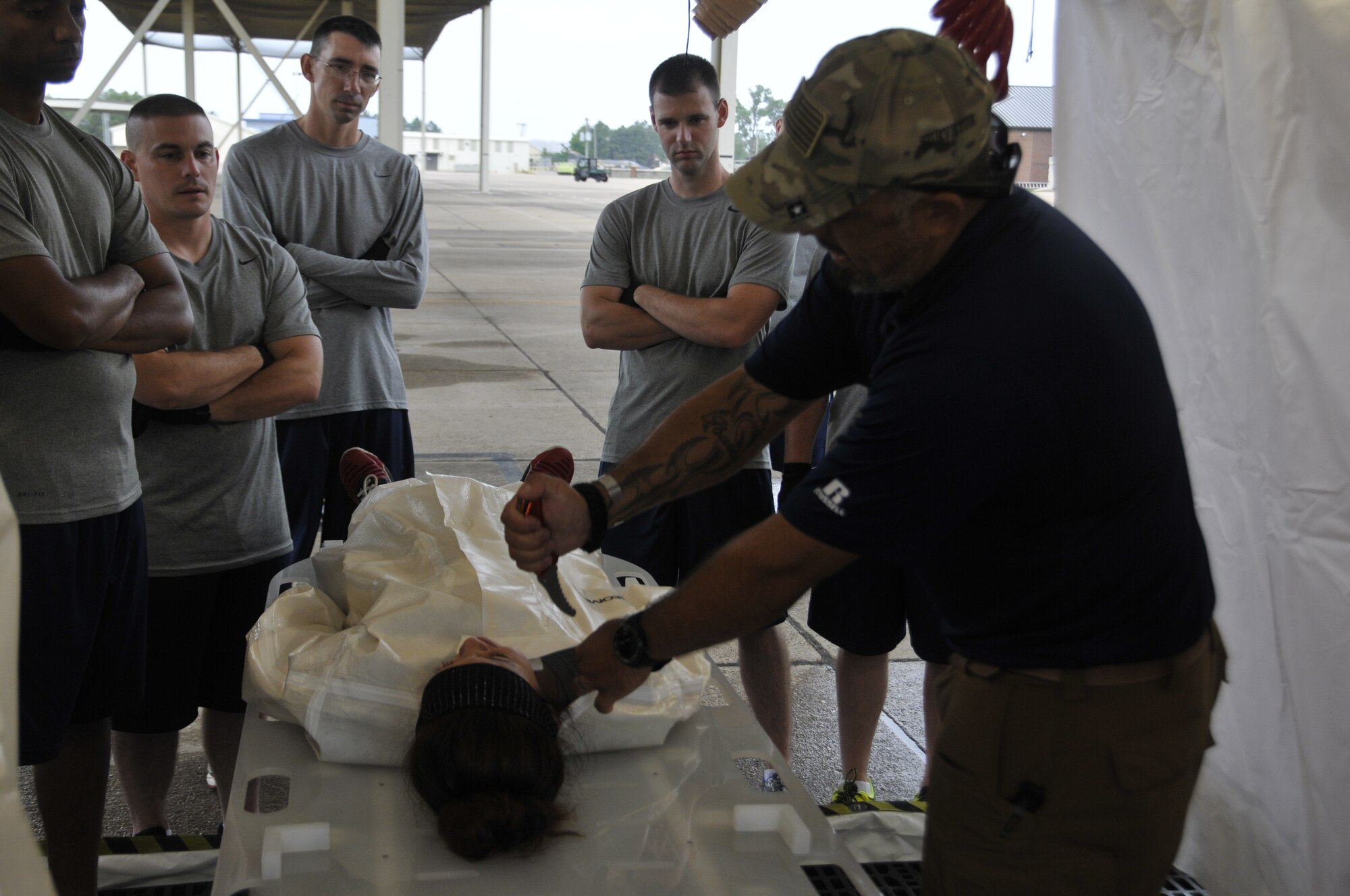 Alex Ibarra, Senior CBRN Training specialist, demonstrates how to cut clothing off contamination victims for Airmen from the 188th Wing during decontamination training at Ebbing Air National Guard Base, Arkansas, July 17. The volunteers, who were from various parts of the wing, learned how to set up a decontamination tent and clean victims of various chemical or nuclear hazards. This training will aid the wing in its mission to support Arkansas citizens in times of disaster. (U.S. Air National Guard photo by Staff Sgt. John Suleski/released)