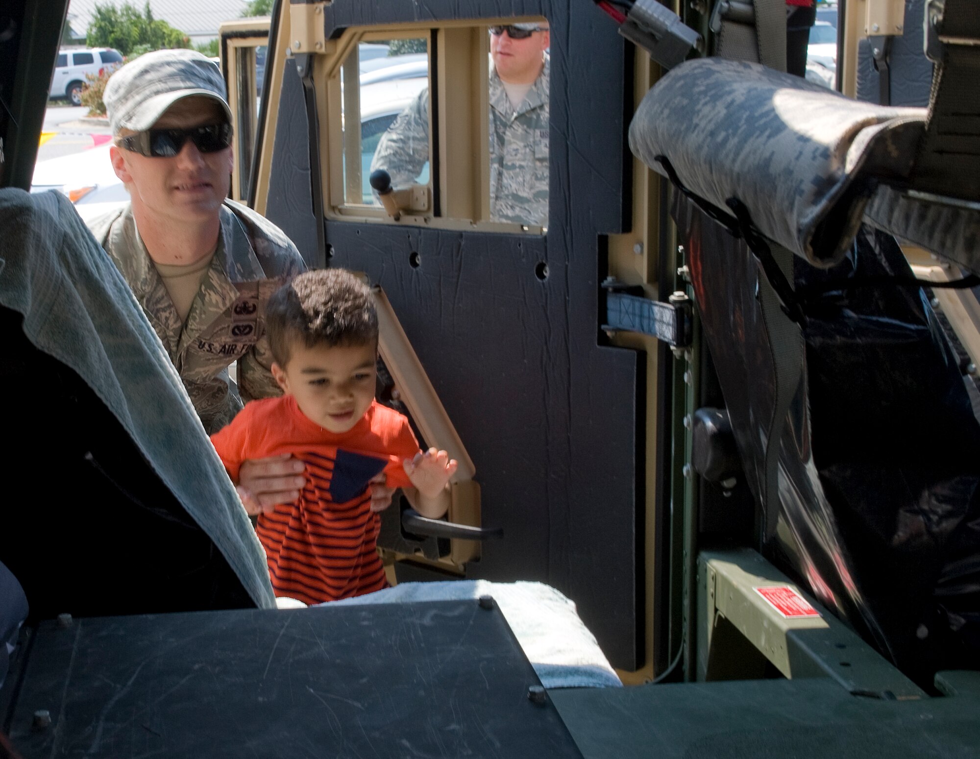 Senior Airman Thomas Johnson, 1st Special Operations Civil Engineer Squadron Explosive Ordinance Disposal technichian, helps a child into a Humvee during the 16th Annual Truck Day at the Destin Community Center in Destin, Fla., Aug. 7, 2014. “Events like this are a great way for us give back to the local community,” said Johnson. (U.S. Air Force photo/Senior Airman Kentavist P. Brackin)