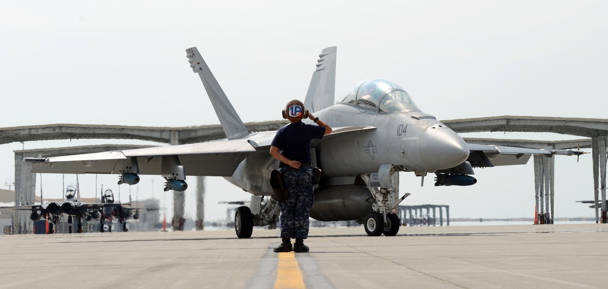 Navy Seaman Amy Martins, VFA 154 maintainer, salutes a F-18F Super Hornet as it taxis to take-off Aug. 8, 2014, at Mountain Home Air Force Base, Idaho. VFA 154, the Black Knights, were invited to come out and use the MHAFB range complex by the 389th Fighter Squadron, T-Bolts, as a way for both squadrons to perform combat training scenarios. (U.S. Air Force photo by Senior Airman Benjamin Sutton/Released)